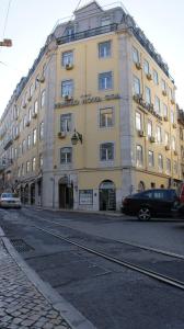 ein großes Gebäude auf einer Straße mit vor der Tür geparkt in der Unterkunft Pensao Nova Goa in Lissabon