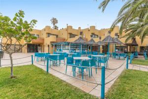 a restaurant with blue tables and chairs in front of a building at Casa Del Caballero Corralejo in Corralejo