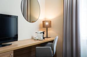 a room with a desk with a television and a mirror at Leonardo Boutique Hotel Salzburg Gablerbräu in Salzburg