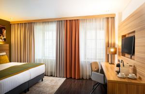 a hotel room with a bed and a desk at Leonardo Boutique Hotel Salzburg Gablerbräu in Salzburg