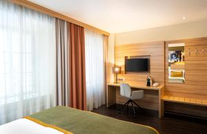 a hotel room with a bed and a desk and a television at Leonardo Boutique Hotel Salzburg Gablerbräu in Salzburg