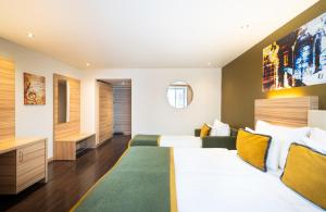 a hotel room with two beds and a television at Leonardo Boutique Hotel Salzburg Gablerbräu in Salzburg