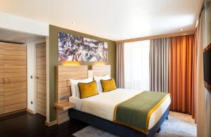 a bedroom with a large bed with yellow pillows at Leonardo Boutique Hotel Salzburg Gablerbräu in Salzburg
