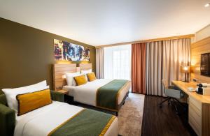 a hotel room with two beds and a desk at Leonardo Boutique Hotel Salzburg Gablerbräu in Salzburg