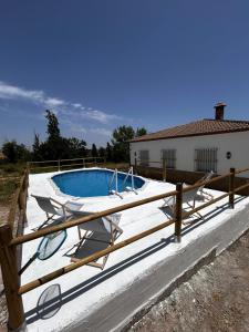 a swimming pool with two chairs and a wooden fence at Casa rural de encanto en plena Serranía de Ronda in Ronda