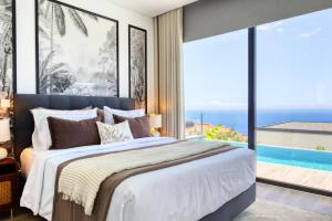 ein Schlafzimmer mit einem großen Bett und einem großen Fenster in der Unterkunft Villa Arco-Iris, a Home in Madeira in Arco da Calheta