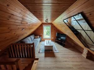 a living room in a log cabin with a couch and a tv at Atokvėpis Alantos kaime in Alanta