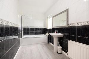 a bathroom with a sink and a tub and a mirror at Stylish 3 or 4 Bed House and Parking in Manchester +22 photos