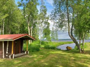 a cabin in the grass next to a body of water at Cozy cottage on lake in Iokela
