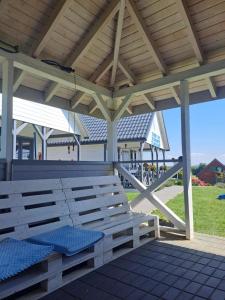 a wooden bench sitting under a pavilion with a porch at Domki u Ani Rusinowo in Rusinowo