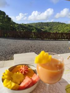 a bowl of fruit and a drink on a table at Les Hauts de Beline Petit-Havre in Le Gosier