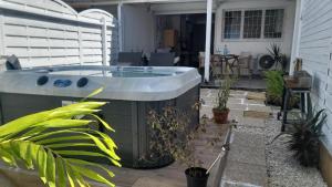 a hot tub on a patio with plants at Le Maracuja Parenthèse tropicale & jacuzzi privé in Sainte-Anne