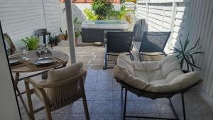 a patio with chairs and a table and a tub at Le Maracuja Parenthèse tropicale & jacuzzi privé in Sainte-Anne +5 photos
