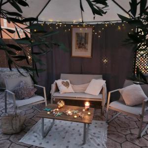 a patio with a couch and a table and lights at Potamos Townhouse & Shared Garden in Potamós +8 photos