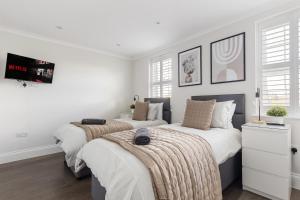 two beds in a bedroom with white walls at Mallside Meadows - Hot Tub, Games Room, Garden in New Southgate