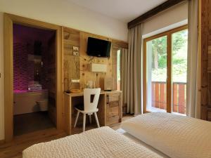 a bedroom with a desk and a bed and a television at Hotel Garni Royal in Arabba