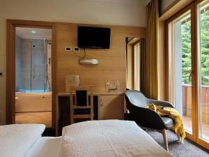 a bedroom with two beds and a chair and a television at Hotel Garni Royal in Arabba