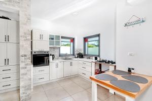 ハッド・ネスにあるסוויטות טיפאני של רשת לב הגולן - 3 סוויטות מדהימות עם בריכה פרטיתの白いキャビネットと木製のテーブルのあるキッチン