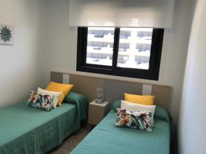 two green beds in a room with two windows at Lovely modern two bedroom apartment in Arenales del Sol +36 photos