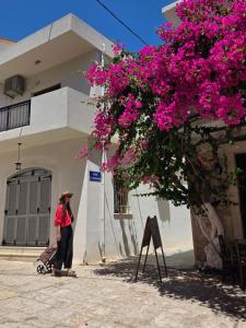 a woman standing next to a building with pink flowers at Theasea Stylish Residences in Panormos Rethymno