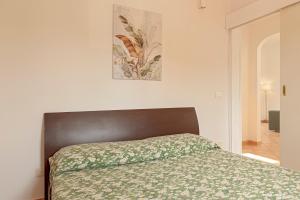 Una cama en un dormitorio blanco con una manta verde. en ELEGANTE APPARTAMENTO A POCHI PASSI DAL MARE E DAL CENTRo, en Livorno