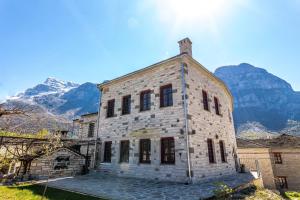an old stone building with mountains in the background at Antalki Experience Apartments in Papingo