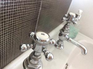 a chrome bathroom sink with a mirror and a tub at Springwood in Seahouses