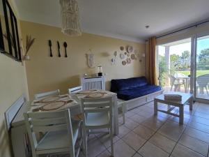 een woonkamer met een tafel, stoelen en een bank bij Appartement T2 avec terrasse, résidence front de mer in Les Sables-dʼOlonne