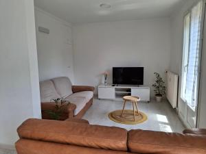 a living room with a couch and a tv at Maison aux portes de Caen in Ifs