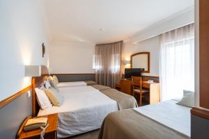 a hotel room with two beds and a desk at Hotel Santo Amaro - SA Hotels in Fátima