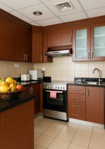 迪拜Goodwill Holidays ,Near Jumeirah Beach Residence 1的厨房配有木制橱柜,柜台上放着一碗水果