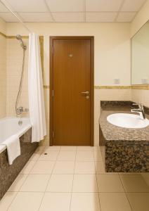 迪拜Goodwill Holidays ,Near Jumeirah Beach Residence 1的带浴缸和水槽的浴室以及木门。