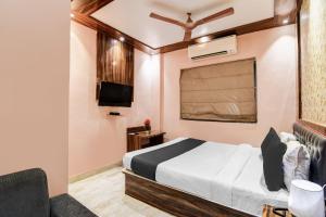 a hotel room with a bed and a tv at Collection O Park Circus in Kolkata