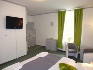 Habitación de hotel con cama, TV y cortinas verdes en Pension Kamenný Dvůr, en Mariánské Lázně