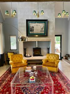 a living room with yellow chairs and a glass table at Underberg - The Burn - Solar Powered in Underberg