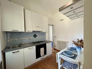 cocina con armarios blancos, fregadero y mesa en Square Apartment in Centro città, en Sarzana