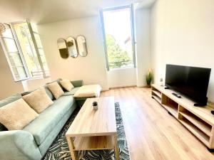 a living room with a green couch and a flat screen tv at Le Provençal Colline St Jacques in Cavaillon
