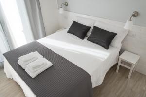 a large white bed with black pillows and a table at B&B Bucci 54 in Morciano di Romagna