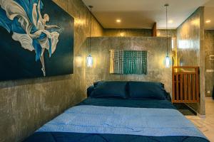 a bedroom with a blue bed with a painting on the wall at Amshiga 4 in Jimbaran +7 photos