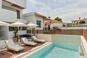 a house with a swimming pool with chairs and an umbrella at Palm Boutique Suites in Pefkochori