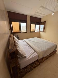 a bedroom with a large bed with white sheets and windows at Berber vibes in Tamraght Ouzdar