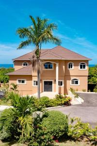 a house with a palm tree in front of it at Seaview Penthouse Retreat 4 Beds 3 Baths Stay in Whitehouse