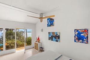 a bedroom with a ceiling fan and paintings on the wall at Chambres d'hôtes - La Moustelle in La Croix-Valmer