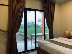 a bedroom with a bed and a large glass window at Green House Tetebatu in Tetebatu