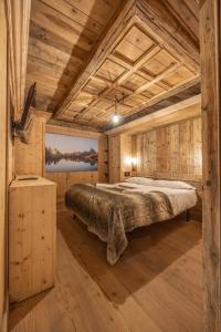 a bedroom with a large bed in a room with wooden walls at Casa Aquila, con sauna privata in Chiave
