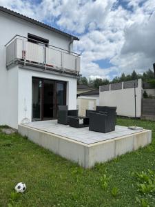 a white house with a patio with chairs and a soccer ball at Stilvolle Wohnung im Erdgeschoss in Kolbermoor