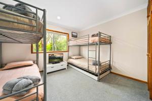 een slaapkamer met 3 stapelbedden en een televisie bij Godfrey's Cottage in Blackheath