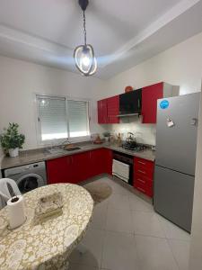 a kitchen with red cabinets and a table and a refrigerator at Salam Beach in Pont Blondin
