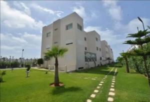 a white building with a palm tree in a field at Salam Beach in Pont Blondin