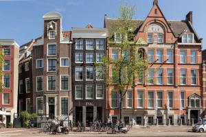 een groep gebouwen aan een straat met fietsen die buiten geparkeerd staan bij INK Hotel Amsterdam - MGallery Collection in Amsterdam